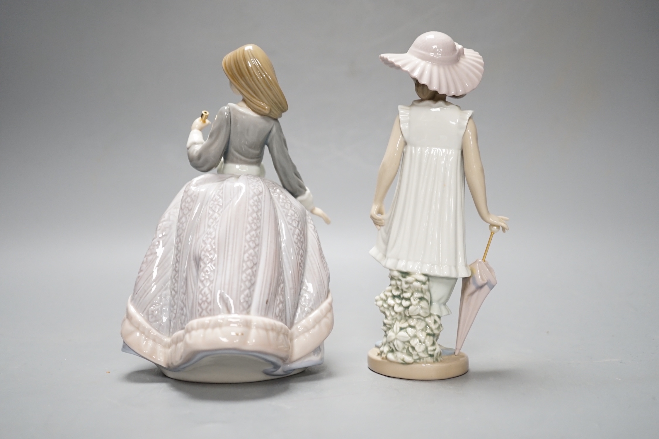 A Lladro figure of a lady with parasol, 18.5cm and a similar Nao figure